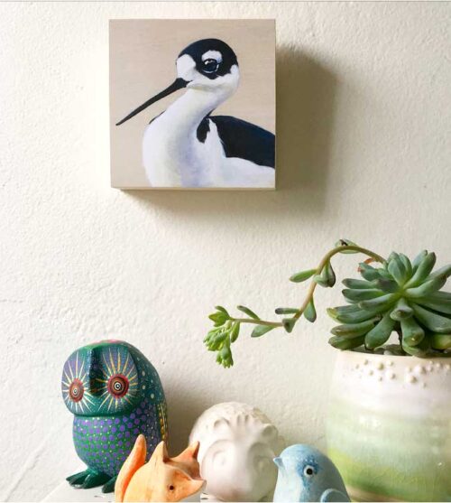 Painting of a black necked stilt by Maggie Hurley hanging on a wall